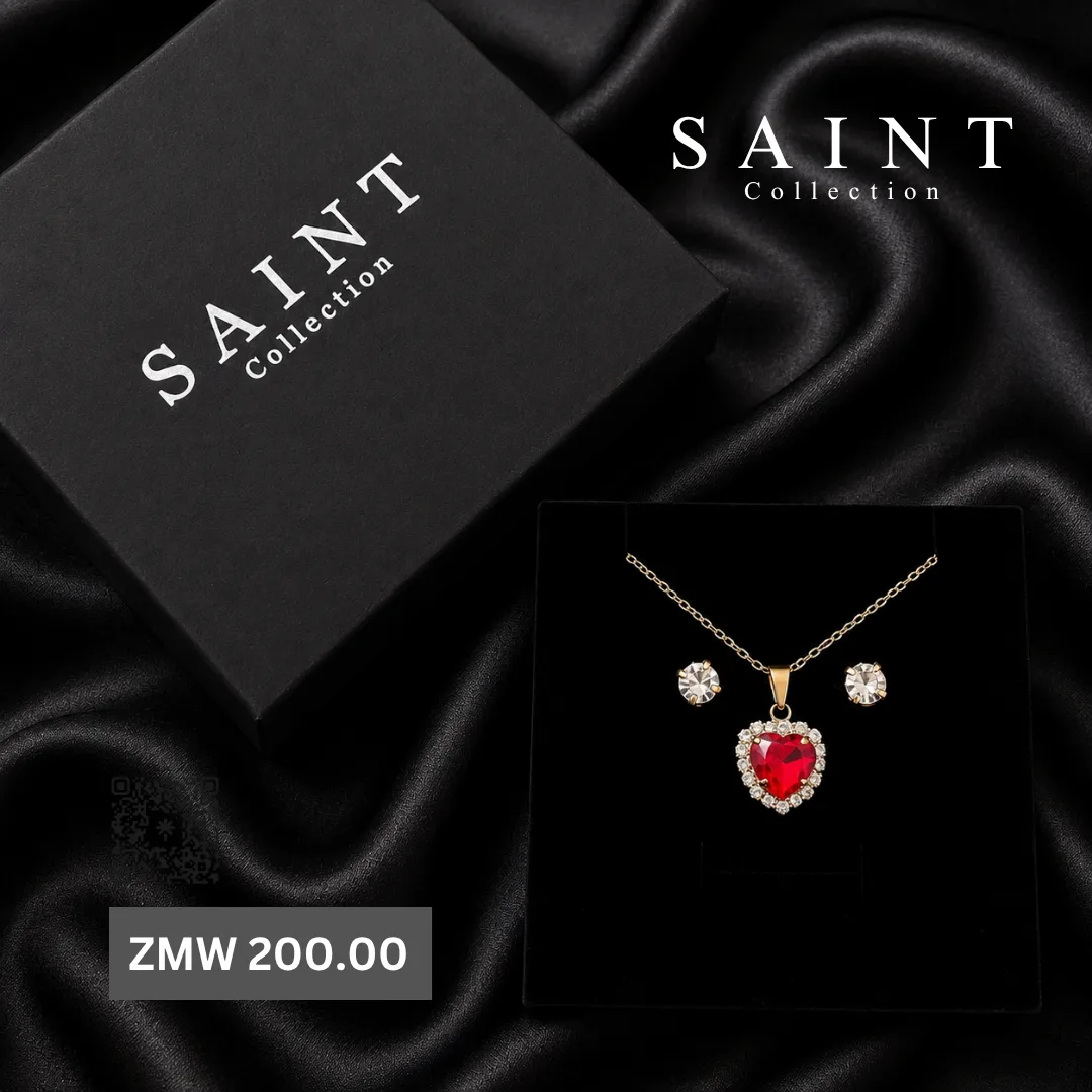 Gold necklace with a red crystal heart pendant and crystal studs, with a Saint Collection gift box on black satin